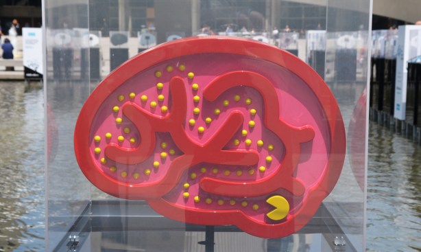 a brain shaped 2 dimensional sculpture, red, made to look like a pac man arcade game, yellow pac man gobbling up yellow dots by Orit Fuchs