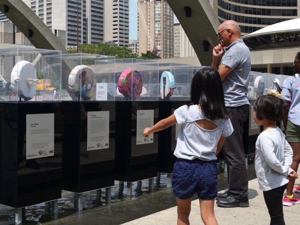 2 girls and a man looking at sculptures shaped like brains 