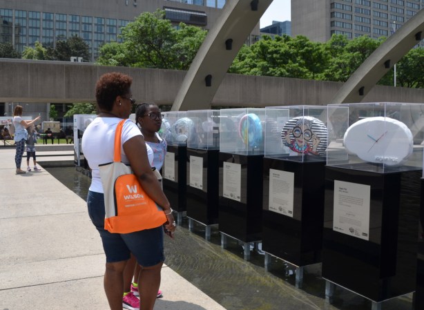 a girl and her mother, looking at brain shaped art sculptures on display at Nathan Phillips Square