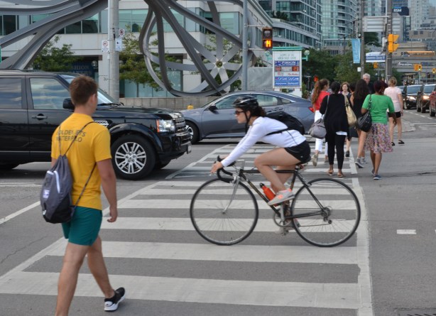 woman on a bike cycles through a red light at Yonge and Queens Quay