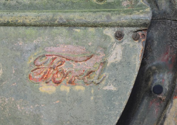 old Ford badge on side of junked car or truck 