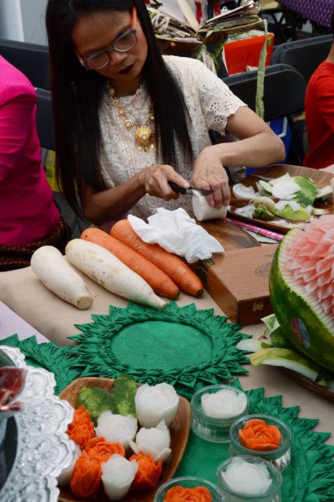 a woman is carving carrots and another white vegetable into flowers 