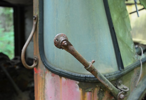 brokwn windshield wiper op the front of a junked and rusty car