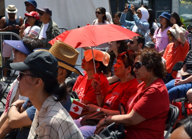 three women in red under a red umbrella watching a Canada day celebration