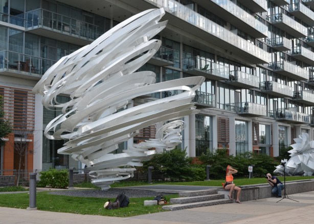 white sculpture that looks like a very large whirlwind or tornado in front of a condo building