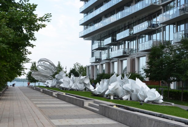 a long white sculpture in a garden in front of a condo