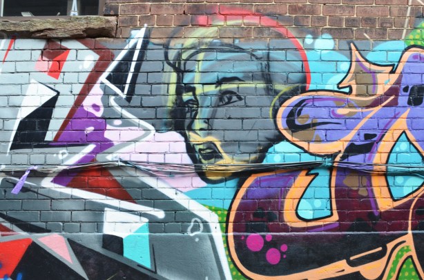 woman's face as part of a mural in Milky Way alley, text mural around her 