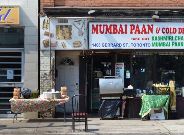 Mumbai Paan shop on Gerrard Street in Little India with a barbeque on the sidewalk, a bucket of corn and a pile of sugar cane