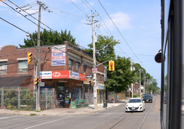 picture taken out the window of a streetcar on Gerrard, an older 2 storey brick building with retail on the lower level, two large old wood hydro poles