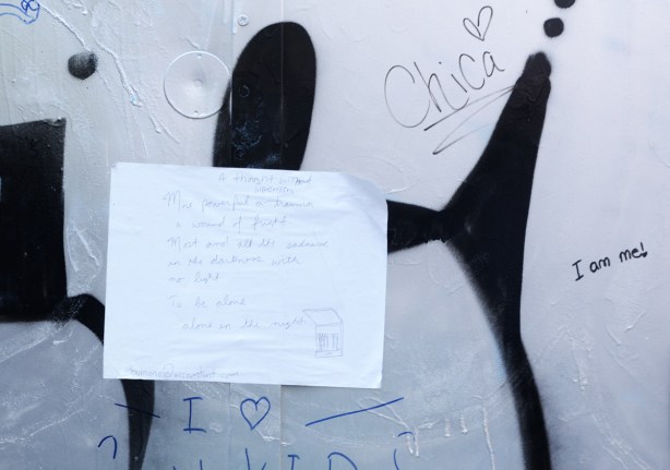 hand written note on white paper written in pen, pasted onto wall in Graffiti Alley 