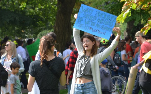 climate strike, rally for action on climate change at Queens Park, a young woman with a blue sign poses for a photo being taken by a friend