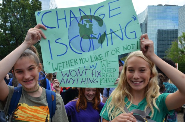 at the climate strike rally at Queens Park on a sunny morning in September, three girls with pale blue signs, Change is coming,