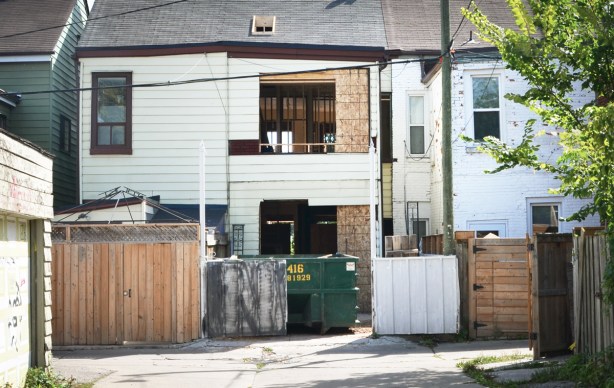 row of backs of houses from lane, house in middle has windows removed and hole in the walls being enlarged