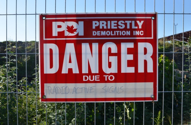 a red and white danger due to sign that someone has written radioactive signs on so sign says danger due to radioactive signs