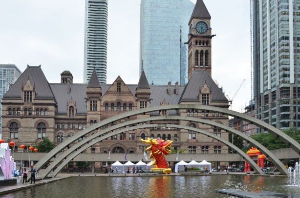 arches over the pool at Nathan Phillips square with old city hall behind, and a red and gold dragon head (very large) on display for dragon festival 