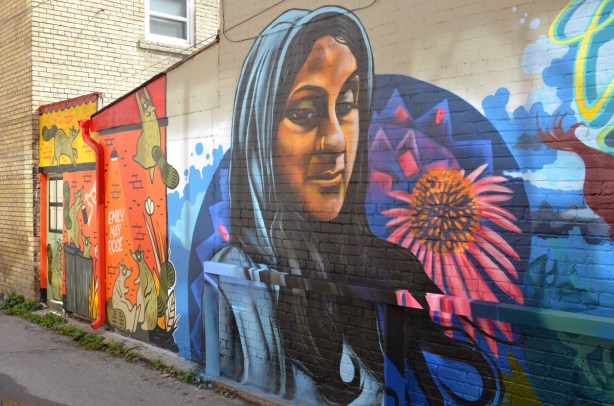 mural my drippin_soul of a woman in blue head scarf beside a large pinkish flower 