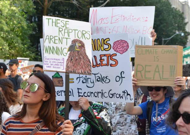 people at Toronto climate strike, walking along Wellesley street with signs, many signs