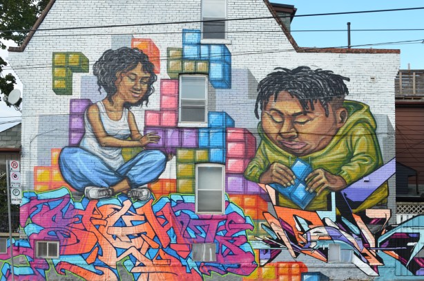 full mural on the side of a house, a mural by elicser of a couple putting tetris shapes together on a wall