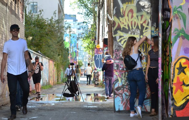 people in graffiti alley, walking, posing for photos, murals, art, 