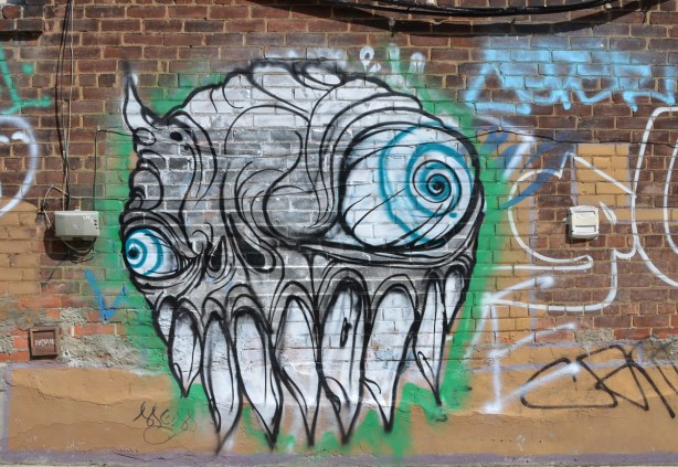 a large grominator graffiti on a brick wall, blue eyes