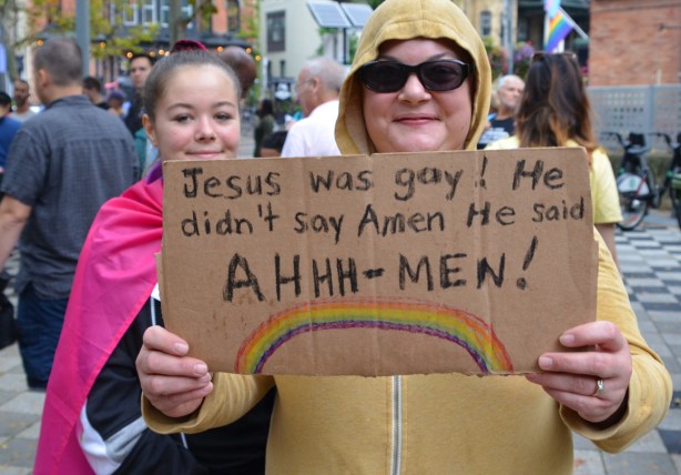 two women, one holding a sign that says Jesus was gay. He didn't say Amen, he said Ahhh men!