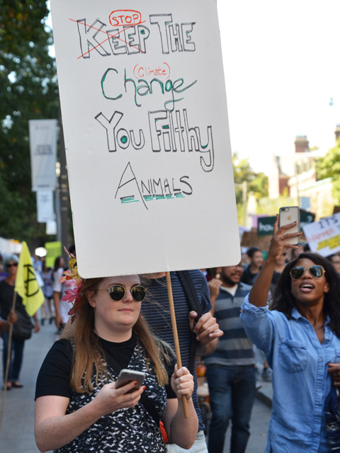 climate strike march in Toronto, a woman holds a sign that says Stop Climate change you filthy animals
