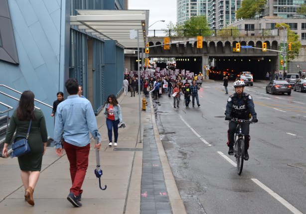 police man on a bike in front of a group of protesters as they start to walk up Yonge street 