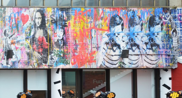 part of a mural made to look like a wall of graffiti including a mona lisa, a man with a camera in triplicate, 