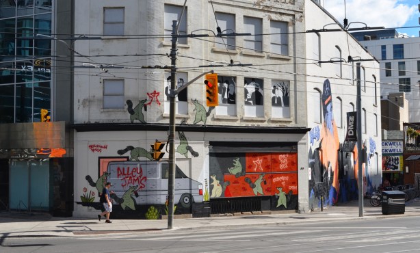mural at the corner of Dundas and Victoria, is actually two murals in one. on the left is one by Emily May Rose, alley jams van and spray painting green raccoons. on the right is a tribute to Killy and Swagger rite, by one day creates 