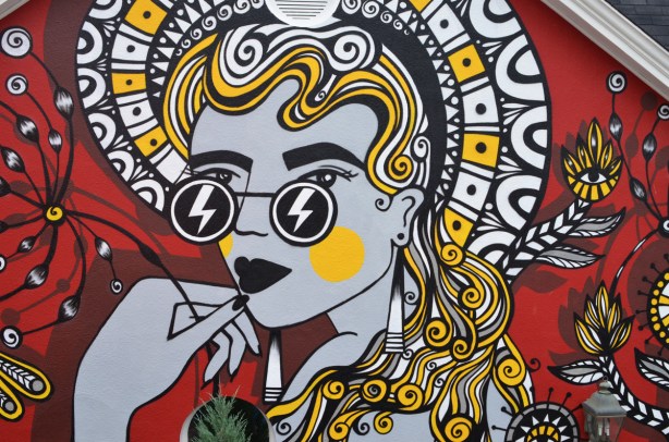 mural of a woman with long hair, stylized, in red, yellow and black and white 