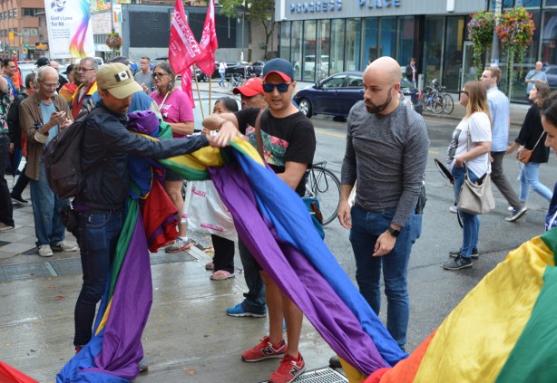 people helping to open up a giant pride rainbow flag 