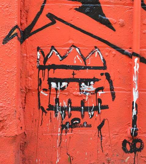 on an orange background, a black line drawing of a square face with four point crown on head and 4 vertical lines as teeth