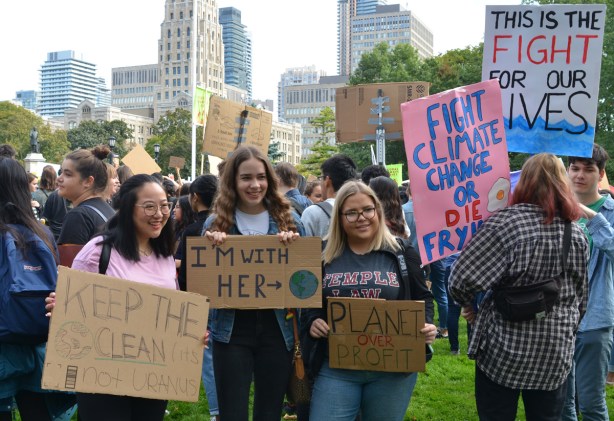 at the climate strike rally at Queens Park on a sunny morning in September, a group of young people with their home made protest signs, some on brown cardboard, and one on pink bristol board,