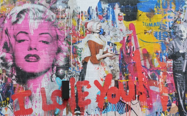 mural made to look like a wall of graffiti including a pink marily munroe, a woman in brown and white dress and bonnet, the word i love you written in red, 