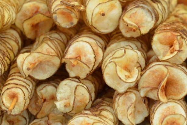 potato spirals, fried and on sticks, looking a pilie of them from the end 