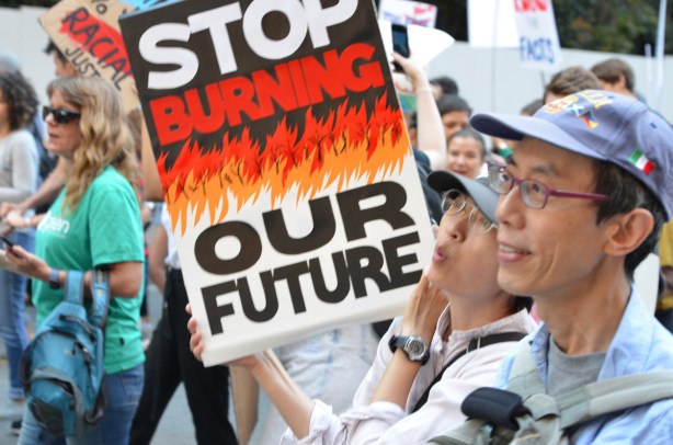 Asian couple with sign that says stop burning our future