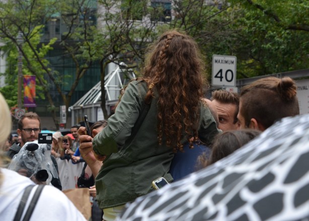someone is talking a selfie with a girl in a green jacket who is being held up by her father, a pro photographer is also taking their picture