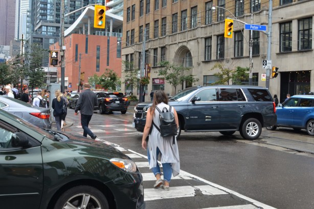 a woman crosses the street on a green light, traffic is jammed because a car has got stuck in the intersection on a red light 