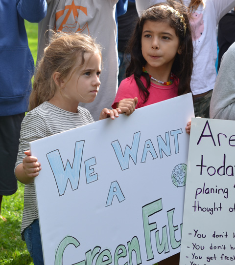 two little girls holding a bristol board protest sign that says we want a green future