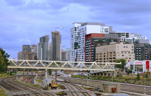 yellow metal pedestrian bridge over the railway tracks, looking from Spadina bridge, condos in the background, lots of tracks, no train 