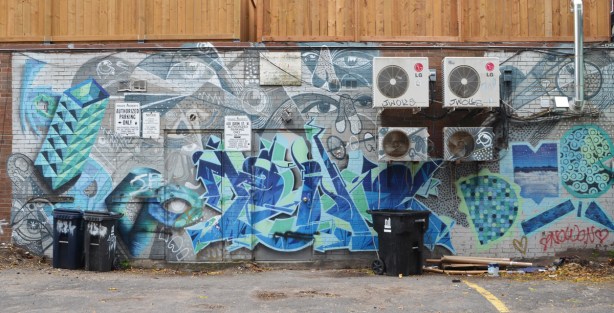older mural on the back of a building in an alley