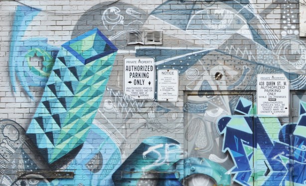 close up view of older mural on the back of a building in an alley