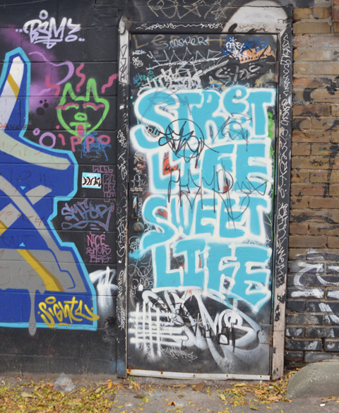 graffiti covered door with turquoise painted words that say street life sweet life