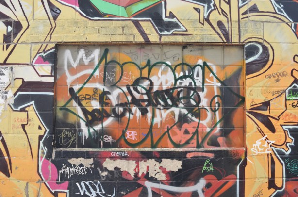 graffiti and paint covering on old window on graffiti covered wall in a lane