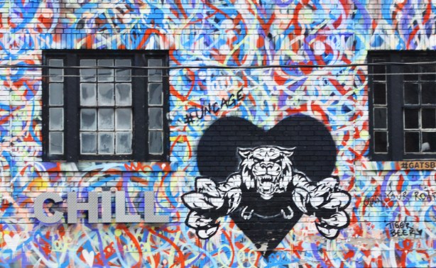 part of the front of a building that has been painted in red, white, blue, and purple squiggles, with a black heart and a roaring tiger leaping out of the heart, also the word Chill in silver block letters