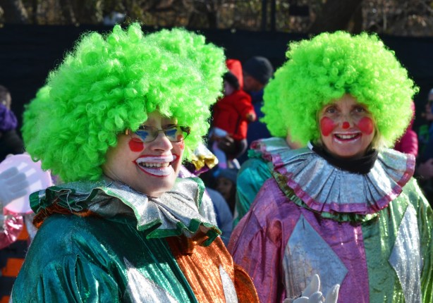 two clowns in Santa Claus parade with red nose and curly green hair, shiny clothing