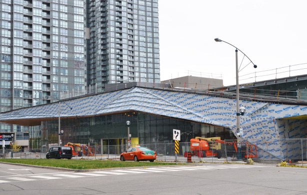 construction of new Canoe Landing Centre on Fort York Blvd, low rise building with sloping roof, tall condo in the background 