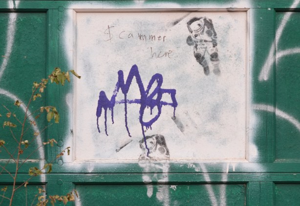 green garage door with a white square, on the square are two black stencils of an astronaut