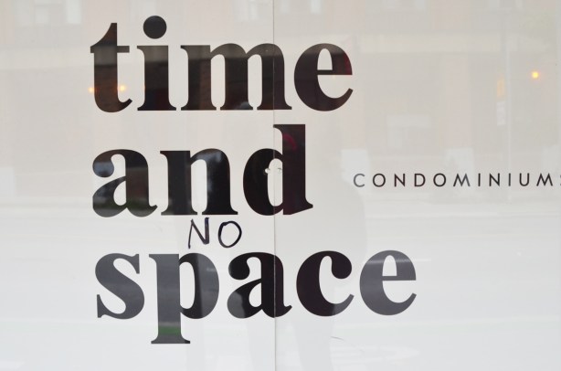 time and space condo hoardings where someone has written the word no in front of space, so you have time and no space condos