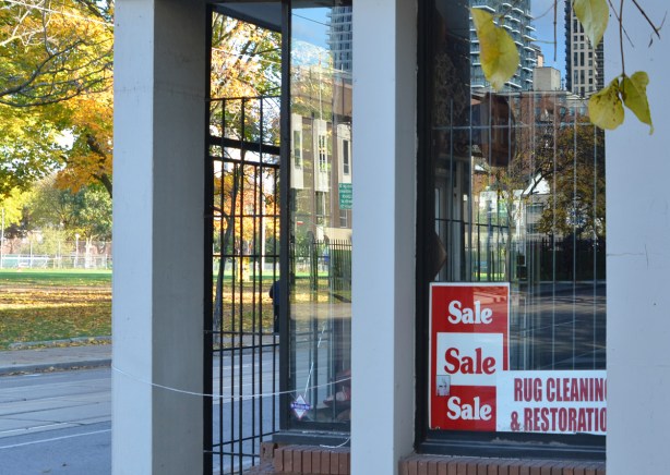 refelctions of autumnleaves and other buildings in a corner window of a rug store 